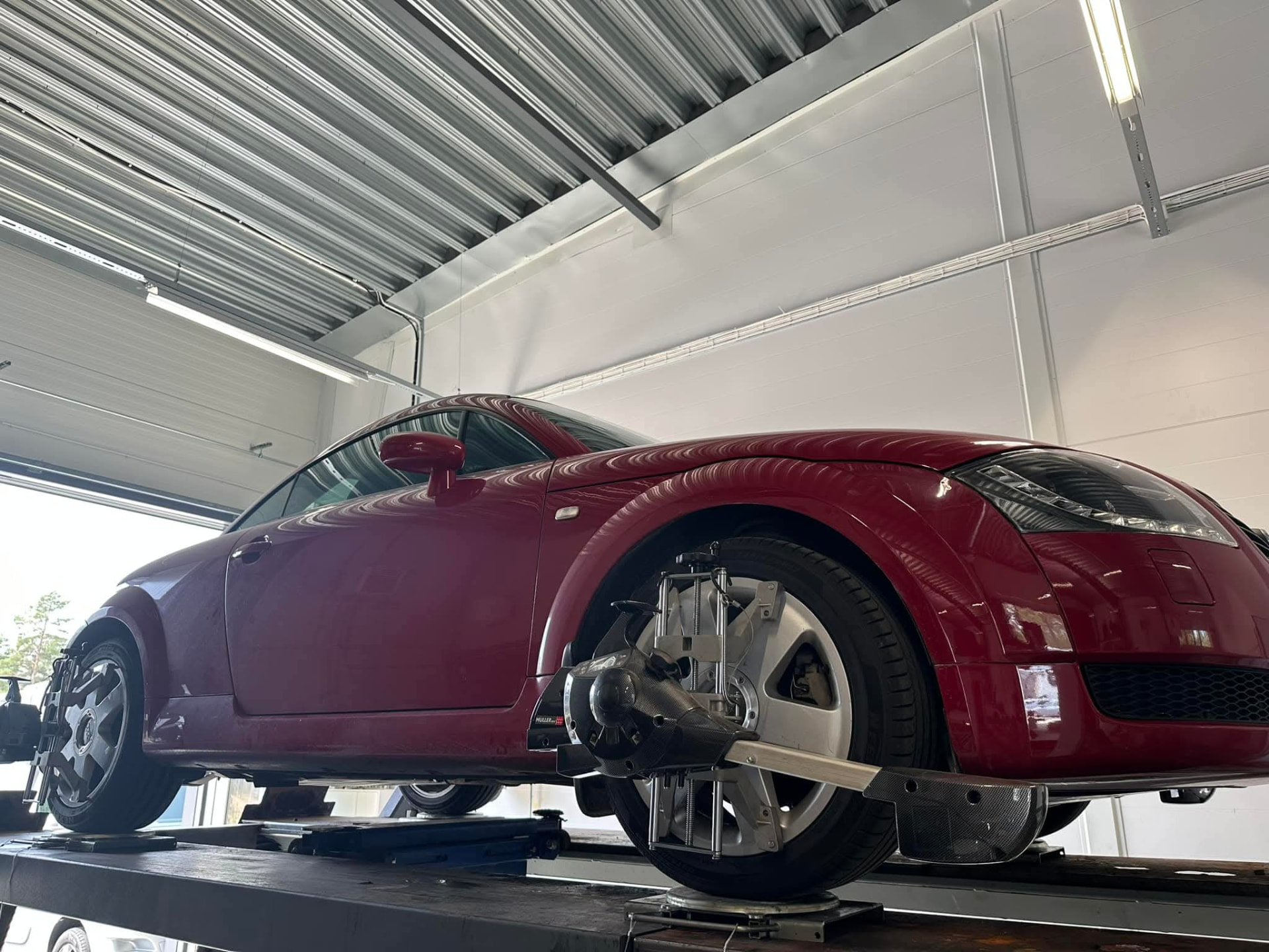 Röd Audi TT på lyft med utrustning för hjulinställning